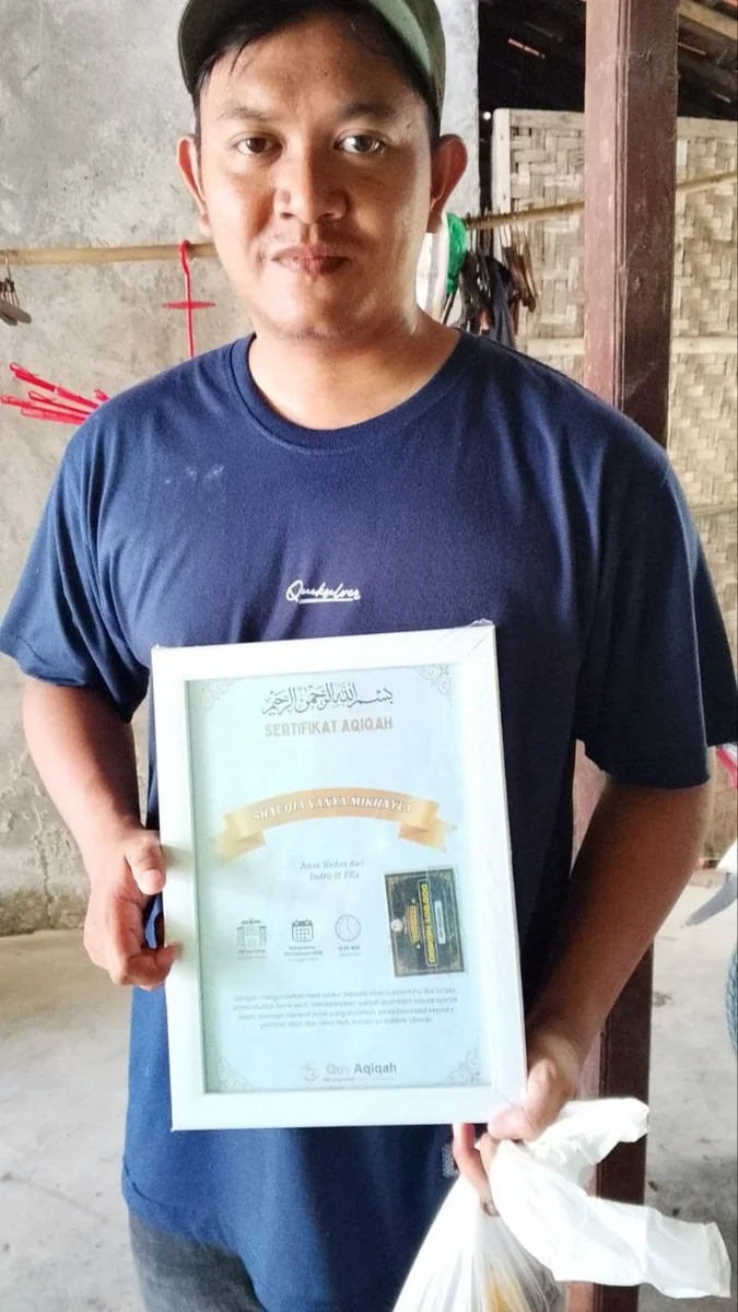 Pelanggan Quy memegang sertifikat aqiqah dan paket yang telah diterima