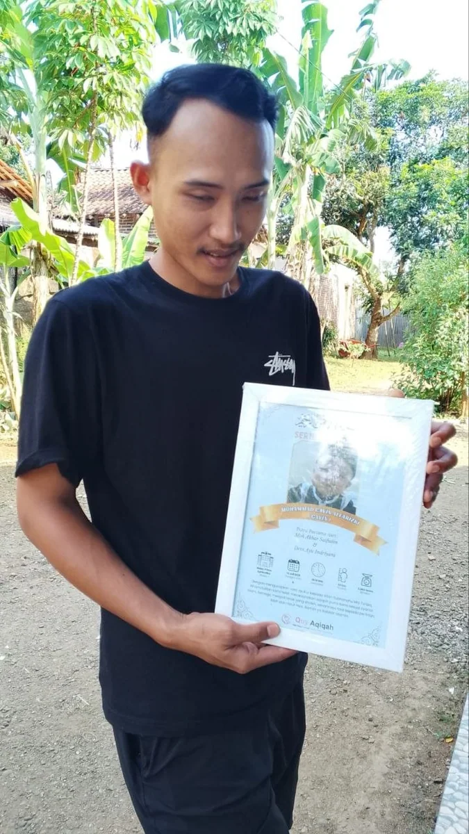 Pelanggan Quy memegang sertifikat aqiqah di halaman rumah